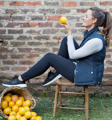 Antonia holding an orange with basket of oranges